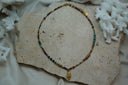Fine multicoloured bead necklace with a gold-tone spiral-shell charm and an asymmetric brown cylindrical bead.