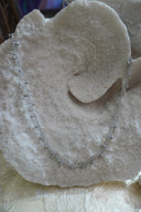 Silver-tone necklace with small round drops spaced along a close-linked chain.