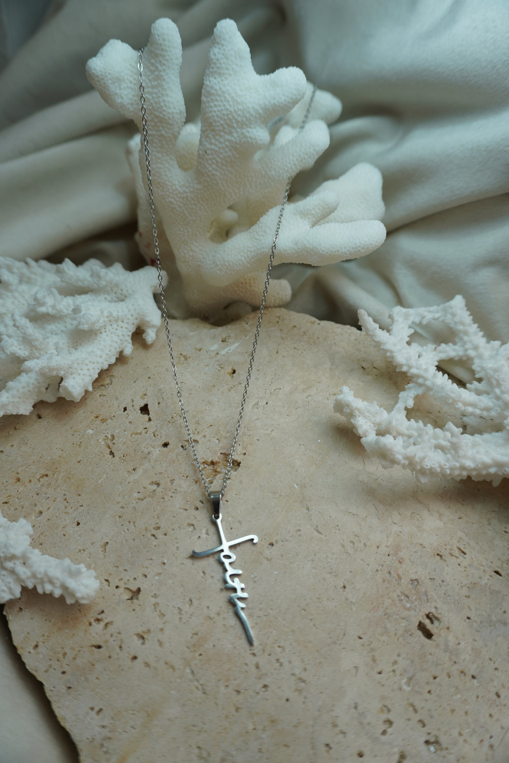 Silver-tone fine chain necklace with a cut-out faith-script pendant incorporating a cross-like outline.