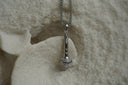 Silver-tone necklace with a miniature microphone pendant and bright decorative details.