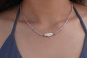Worn view: lilac faceted-bead necklace with gold-tone spacers and an elongated irregular white centre bead.