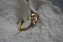 Gold-tone snake-shaped open cuff with green eyes and a curved tail.