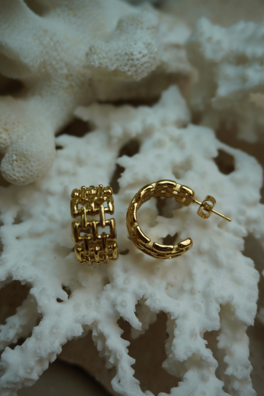 Broad open gold-tone hoop earrings with a rectangular link lattice and visible post backs.