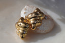 Gold-tone spiral-shell stud earrings with pointed tips and scattered round clear accents.
