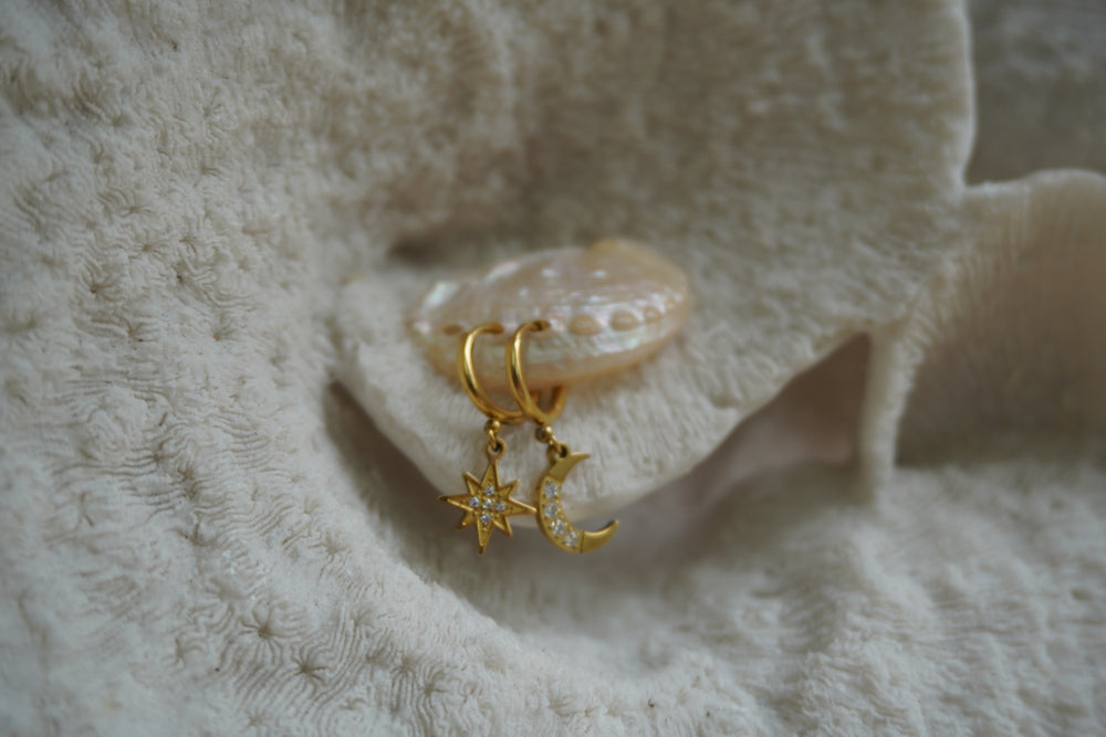 Gold-tone hoop earrings with a clear-accented star and crescent moon charm.
