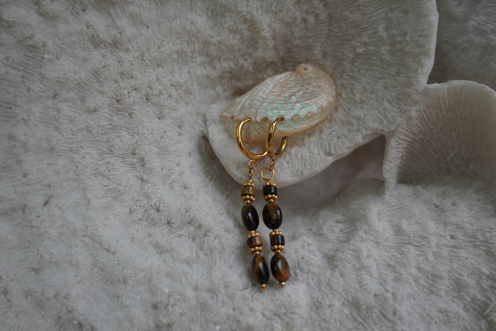 Alternate view: gold-tone hoop earrings with long drops of brown and near-black oval and cylindrical beads.