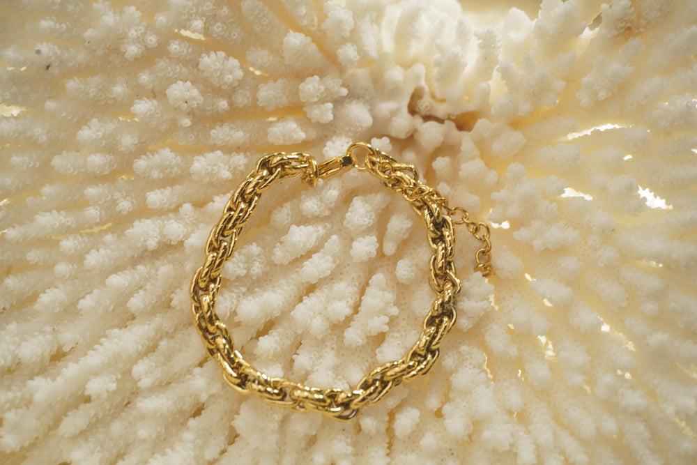 Gold-tone bracelet with chunky interlocking oval links, diagonal markings and an extension chain.