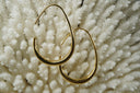Gold-tone elongated open teardrop hoop earrings with tapered upper wires and broader lower curves.