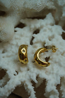Alternate view: rounded open gold-tone hoop earrings with an uneven surface and clear accents in diamond-shaped surrounds.