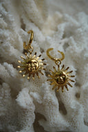 Gold-tone hoop earrings with hanging sun-face charms and pointed rays.