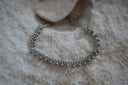 Silver-tone chain bracelet edged with small spherical drops.
