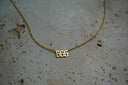 Gold-tone fine chain necklace with cut-out 666 numerals in pointed lettering.