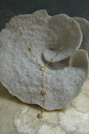 Gold-tone Y necklace with sunburst motifs and small round beads along a fine chain.