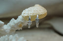 Silver-tone hoop earrings with a clear teardrop-shaped accent on each front.