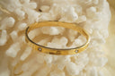 Alternate view: gold-tone bangle with round crossed motifs alternating with clear accents.