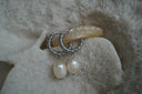 Silver-tone twisted hoop earrings with hanging pale oval beads.