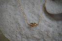 Gold-tone necklace with a smooth central knot shape and fine oval-link chain.