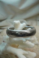 Alternate view: silver-tone bangle with a broad rounded profile and closely spaced ridges.
