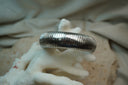 Silver-tone bangle with a broad rounded profile and closely spaced ridges.
