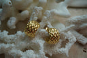 Broad open gold-tone hoop earrings with a repeating diamond-shaped surface pattern.