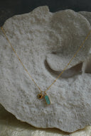 Alternate view: gold-tone necklace with a blue-green elongated charm and a small heart charm.