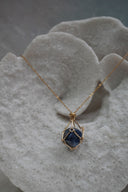 Alternate view: gold-tone necklace with a dark blue rounded centre enclosed by an open geometric framework.