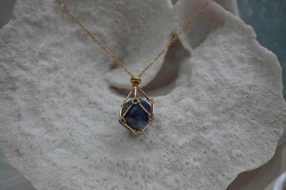 Gold-tone necklace with a dark blue rounded centre enclosed by an open geometric framework.