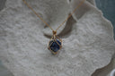 Gold-tone necklace with a dark blue rounded centre enclosed by an open geometric framework.