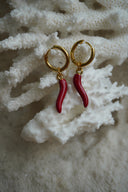 Gold-tone hoop earrings with smooth curved red horn-shaped charms.