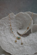 Alternate view: gold-tone necklace with blue centres, sunburst details and two chain drops ending in four-petal shapes.