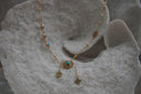 Gold-tone necklace with blue centres, sunburst details and two chain drops ending in four-petal shapes.