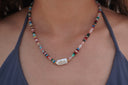 Multicoloured Festival Tide Bead Necklace worn at the neckline, with a pale rectangular centrepiece.