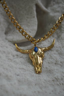 Alternate view: gold-tone link necklace with a bull-skull pendant, sweeping horns and a blue oval accent.