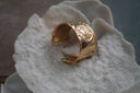Alternate view: broad gold-tone open cuff with a raised sun-face motif, rays and curved cut-outs.