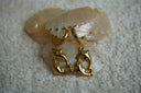 Alternate view: gold-tone hoop earrings with open circular charms formed by two dolphin shapes.