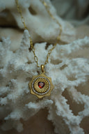 Gold-tone long-link necklace with a radiating medallion, red heart centre and circular border of clear accents.