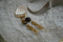 Gold-tone hoop earrings with dark brown oval beads and hanging chain tassels.