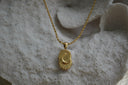 Gold-tone necklace with a crescent moon and short rays on a rounded rectangular tile.