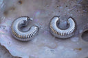 Alternate view: broad silver-tone hoops with fine radiating ribs and rounded contours.