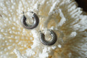 Broad silver-tone hoops with fine radiating ribs and rounded contours.