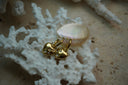 Gold-tone hoops with rounded heart charms and scattered clear accents in square outlines.