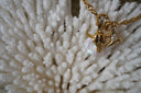Gold-tone necklace with horned skull, boot and pale reflective drop charms.