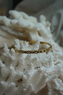 Gold-tone bangle with alternating clear rectangular and round faceted accents.