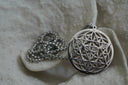 Alternate view: silver-tone necklace with an open disc pendant featuring intersecting triangles over a circular lattice.