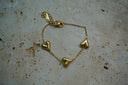 Gold-tone fine chain bracelet with three raised hearts, a clasp and extension chain.