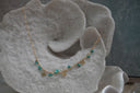 Gold-tone necklace with oval chain details, irregular blue bead drops and four-point star charms.