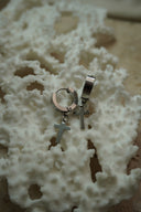 Silver-tone broad hoop earrings with hanging plain cross charms.