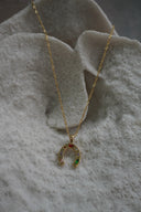 Gold-tone necklace with a horseshoe pendant decorated with multicoloured accents in varied shapes.