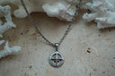 Silver-tone twisted chain necklace with an open circular compass pendant, directional letters and scroll details.
