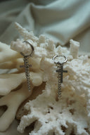 Silver-tone hoop earrings with flat cross charms and longer hanging chain drops.
